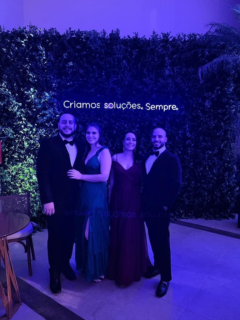 Equipe da Pappo em evento de gala, com neon dizendo Criamos soluções. Sempre.
